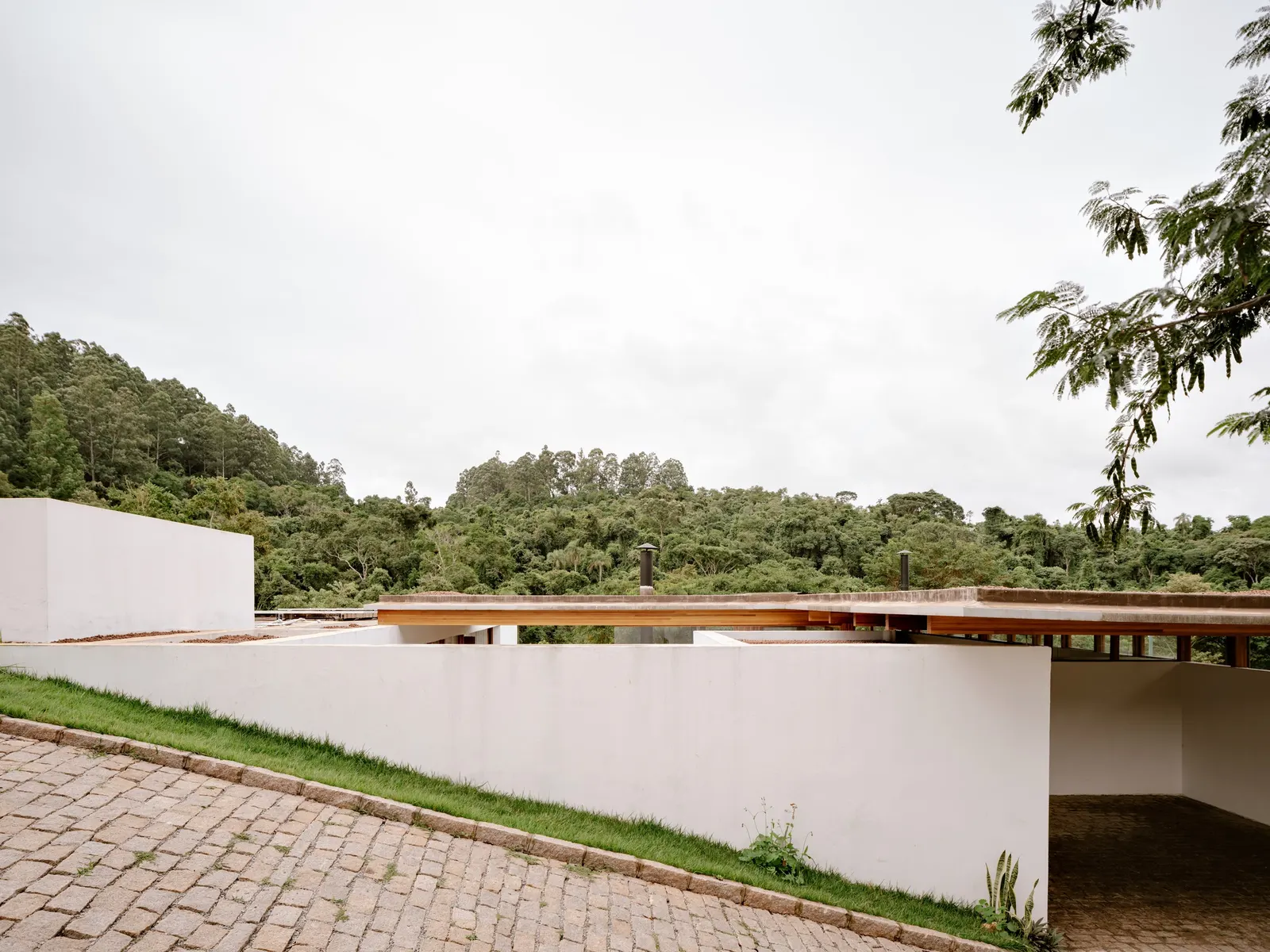 Yoshi House / AR Arquitetos: дом на склоне с кирпичным основанием и лёгкой деревянной надстройкой