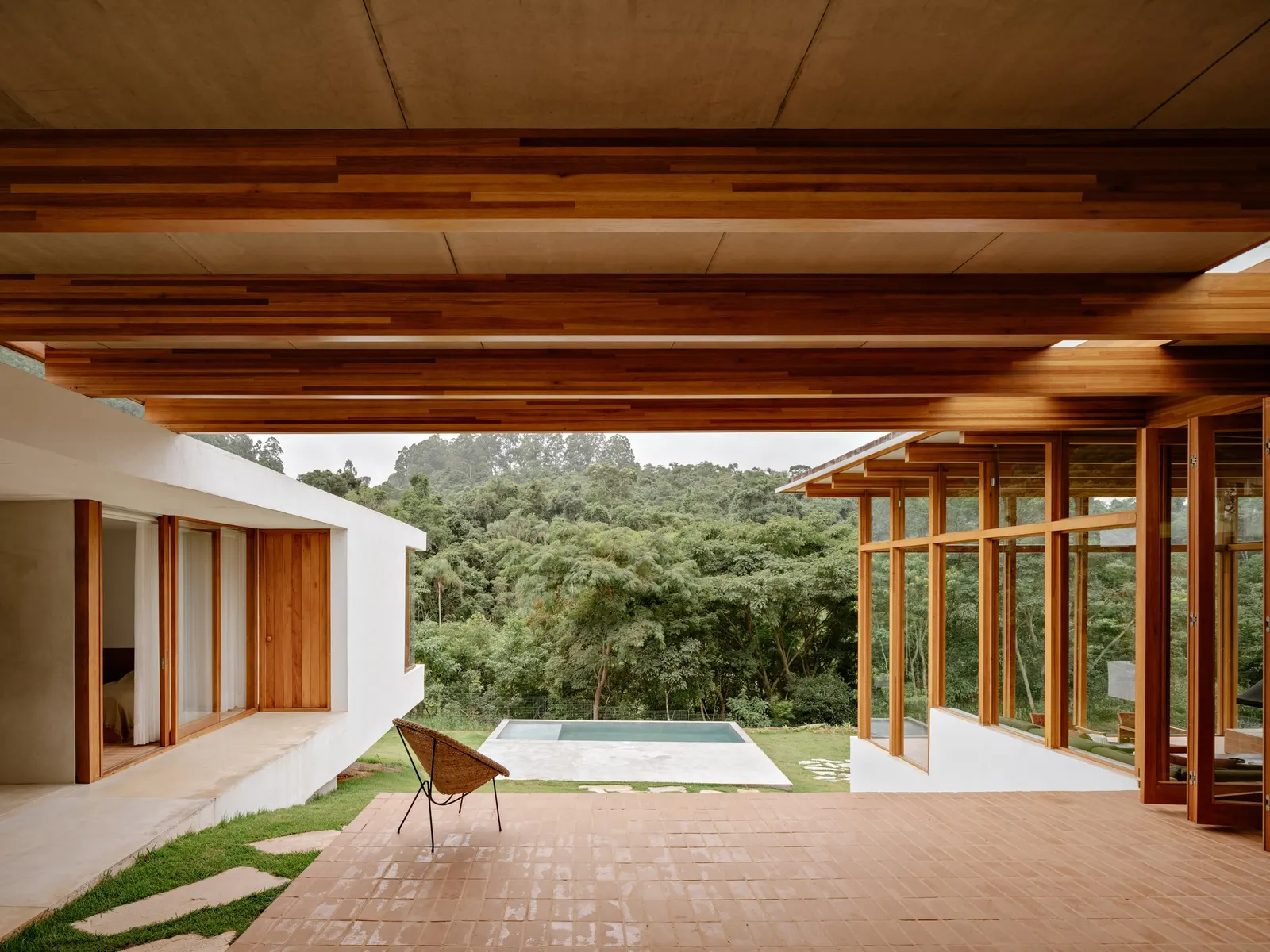 Yoshi House / AR Arquitetos: дом на склоне с кирпичным основанием и лёгкой деревянной надстройкой