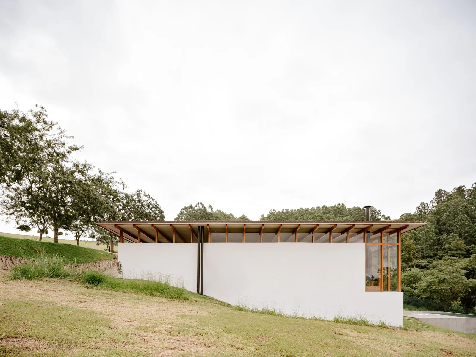 Yoshi House / AR Arquitetos: дом на склоне с кирпичным основанием и лёгкой деревянной надстройкой