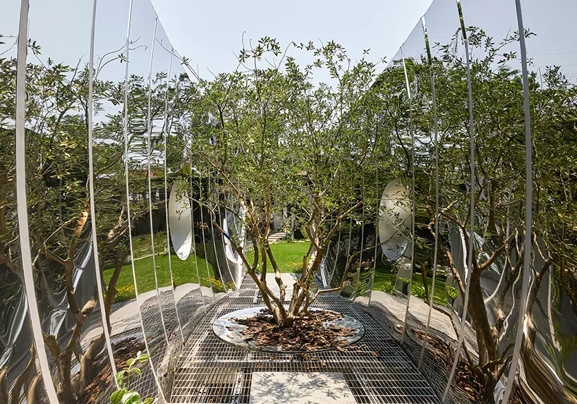 Curved mirrored steel walls multiply one tree into a forest in Infinite Grove pavilion in Shanghai