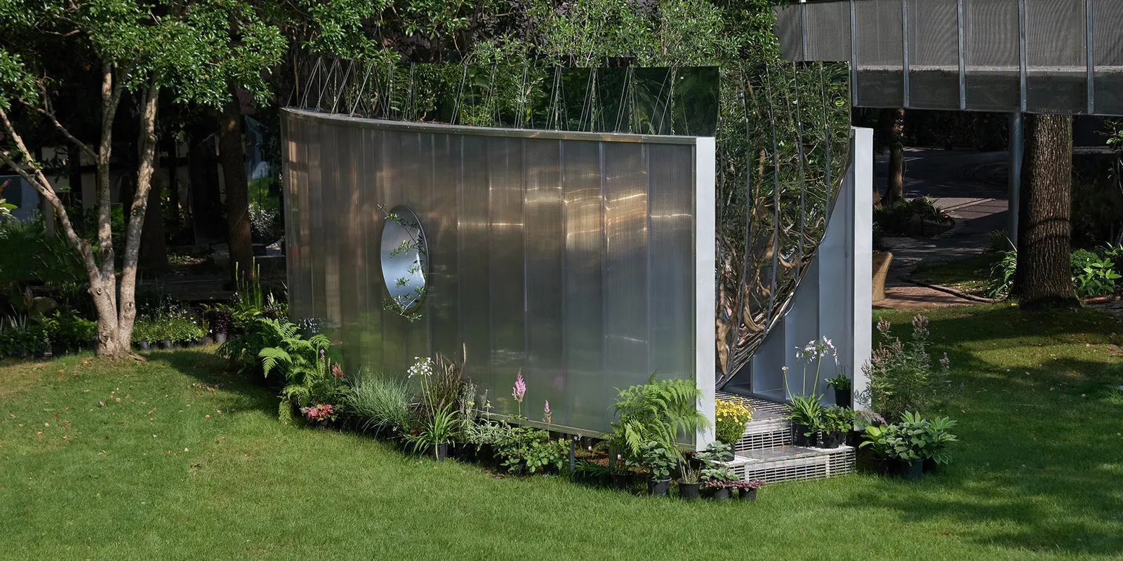 Curved mirrored steel walls multiply one tree into a forest in Infinite Grove pavilion in Shanghai